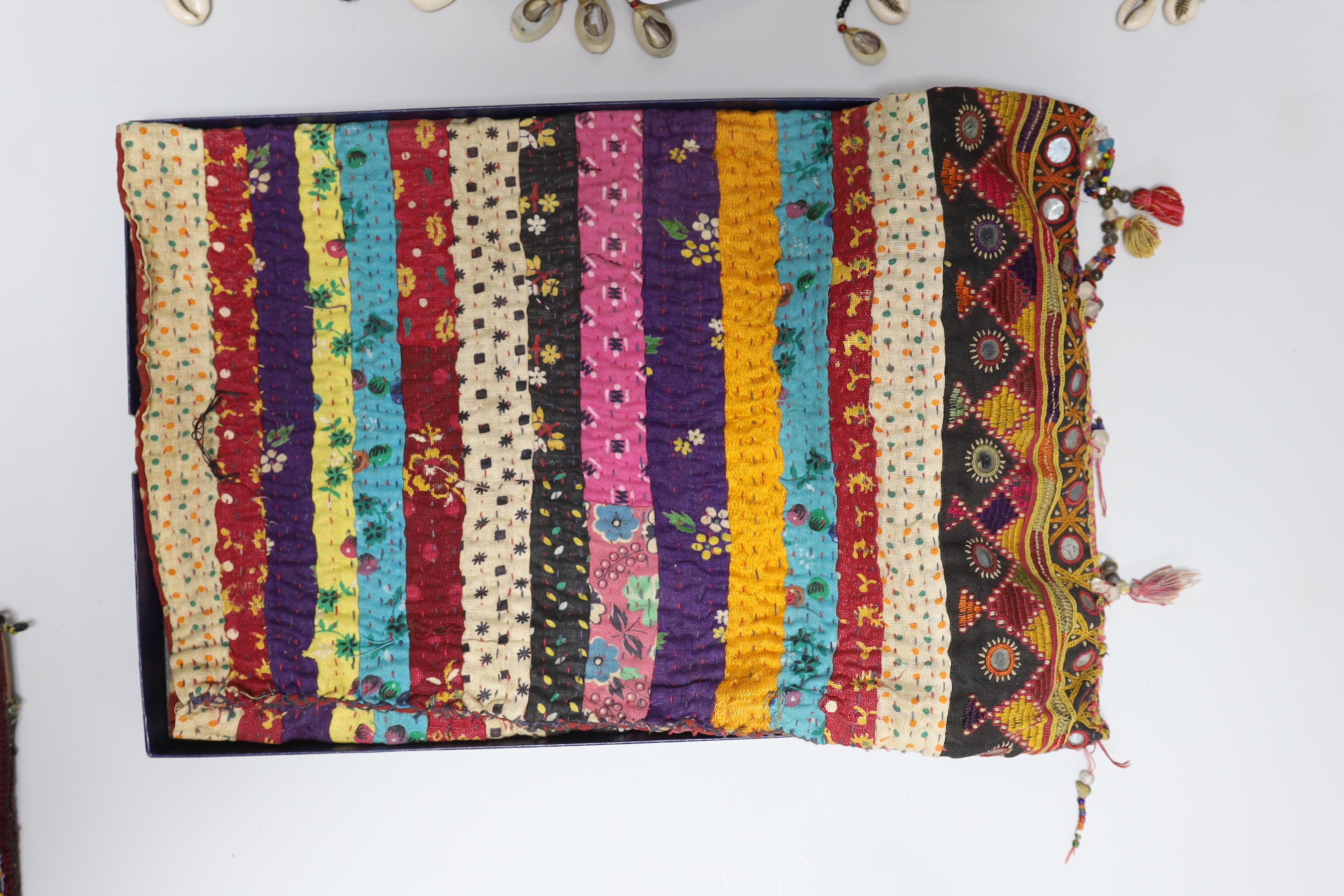 19th and 20th century textiles: An Indian mirrored and patchwork bag, a smaller embroidered bag, an ‘arrow’ shaped mirrored panel and two Omani shell and beaded ‘anchor’ shaped hangings, ‘arrow’ hanging 45cm long (5)